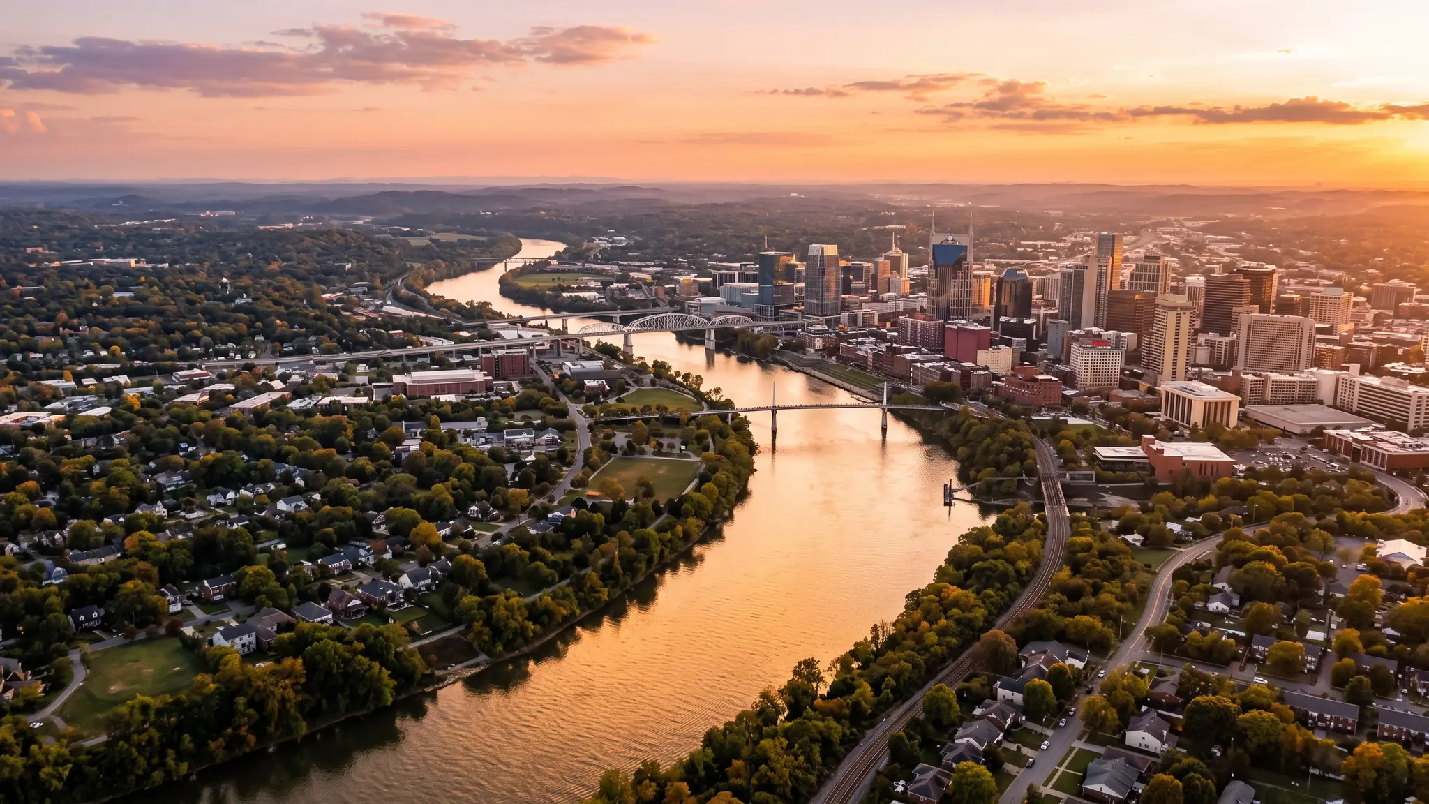 Aerial view of the Cumberland River winding past the Nashville skyline and Middle Tennessee neighborhoods at sunset